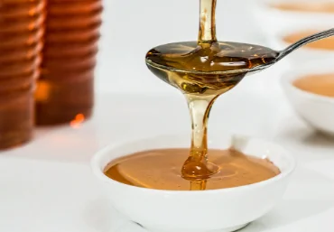honey falling on spoon and cup